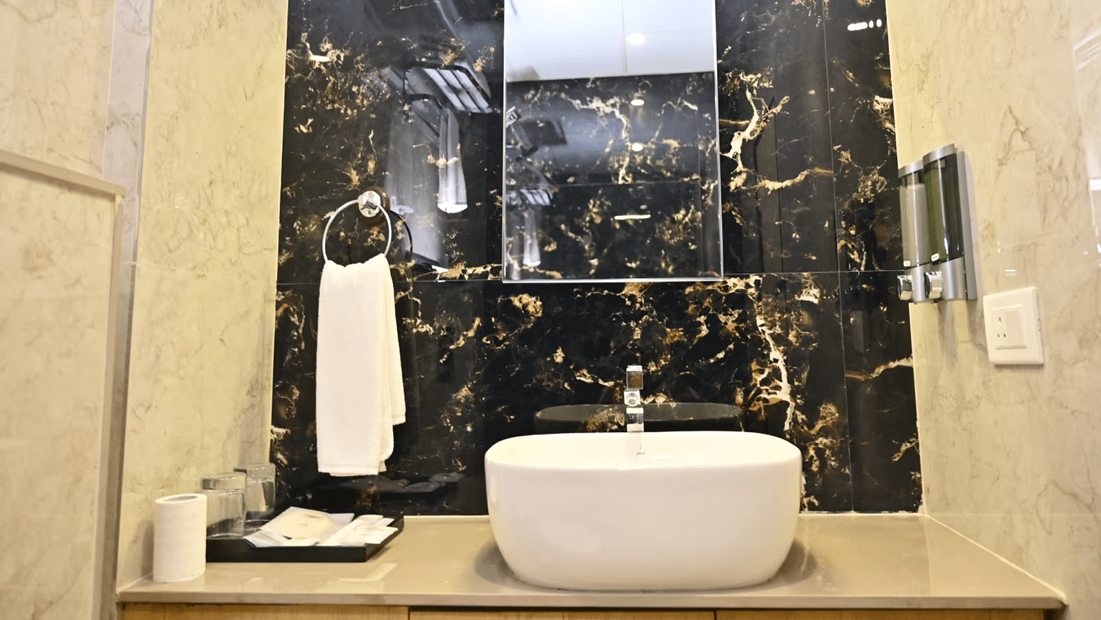 Modern bathroom with marble walls, a sink, and neatly arranged toiletries for a clean and stylish look at TGI Livancia Hillside