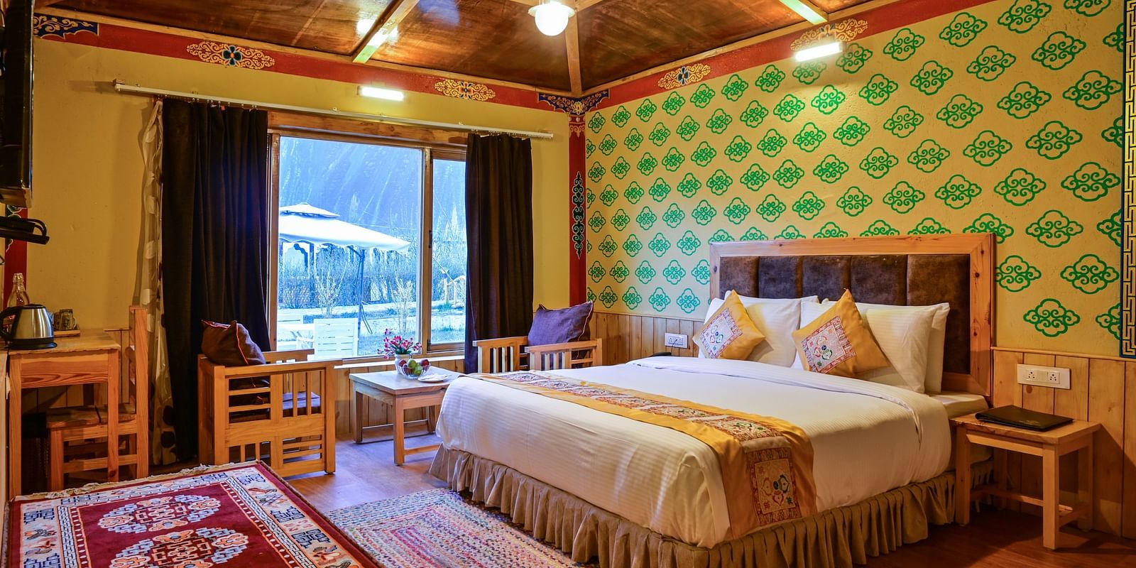 Premium Cottage in White Sands Resort, Ladakh, includes a king size bed, a seating area, and patterned wallpaper.
