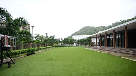 Open lawn with a building on one side and a basketball hoop on the other.