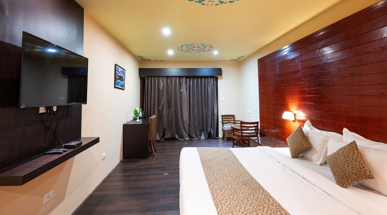 A bed with an artistic painting on the ceiling, adding charm to the room at Avianna Hungry Jack, Gangtok.
