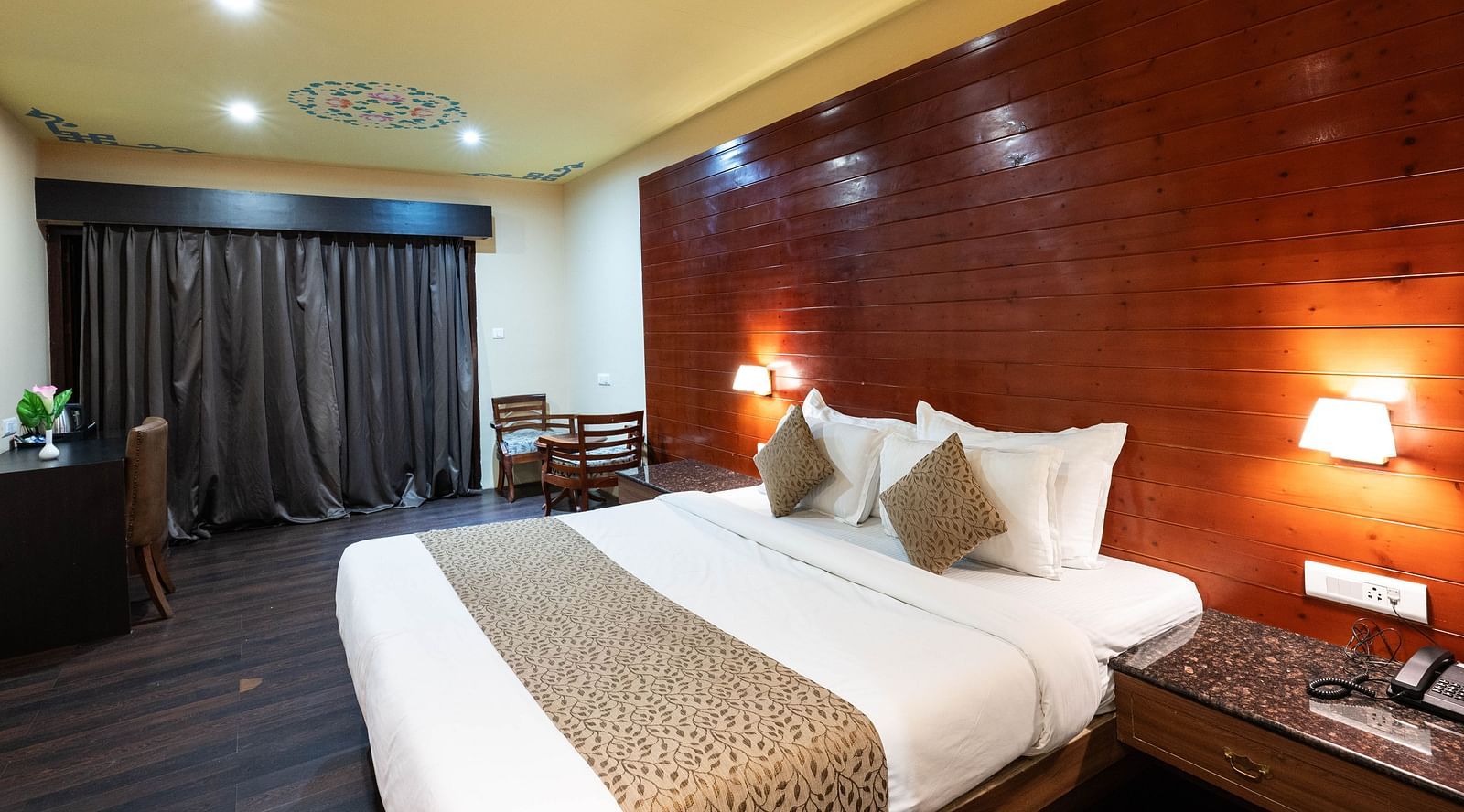 A bedroom with two lights on either side of the bed and a telephone placed on a bedside table next to the bed at Avianna Hungry Jack, Gangtok.