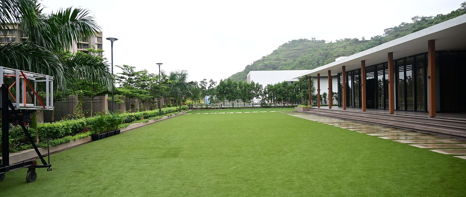 Open lawn with a building on one side and a basketball hoop on the other.