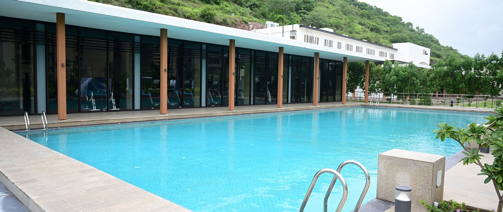 close up image of the swimming pool with the restaurant on the poolside at club charholi, pune