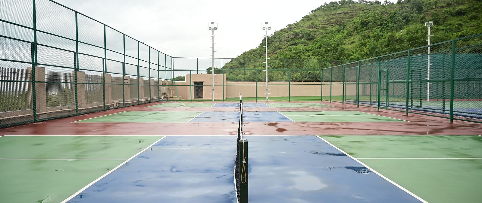 image of the tennis court at club charholi, pune taken from the middle showcasing the net poles