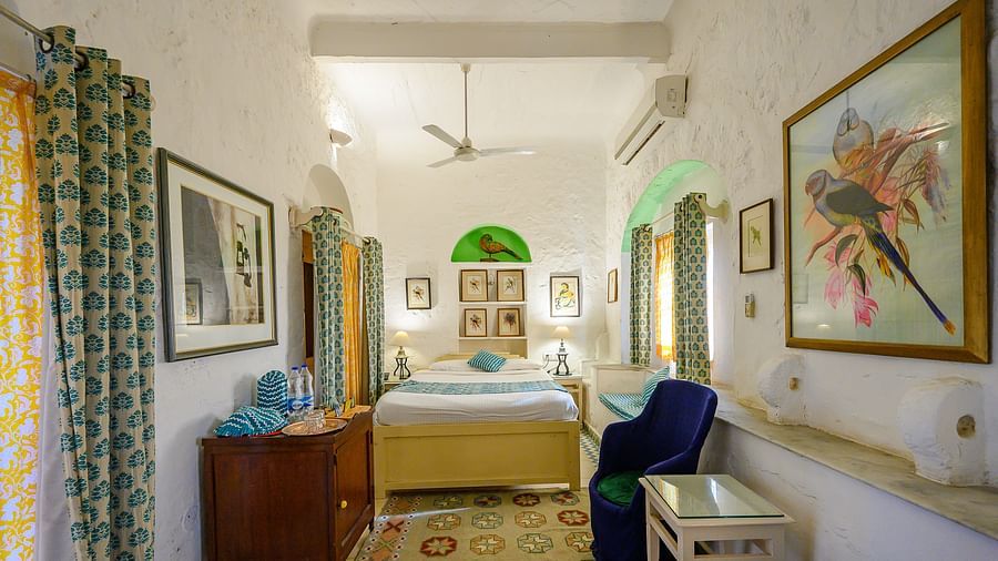 Hill Fort Kesroli 14th Century Alwar - interior view of the Tota Mahal - Garden View - Garden View with single bed, paintings on the wall and green curtains
