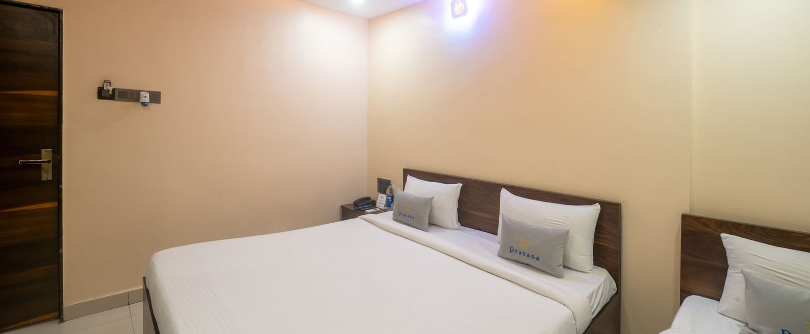 A room at Pravasa Stay, Shirdi, has two beds with white linen, a ceiling fan, and recessed lighting.