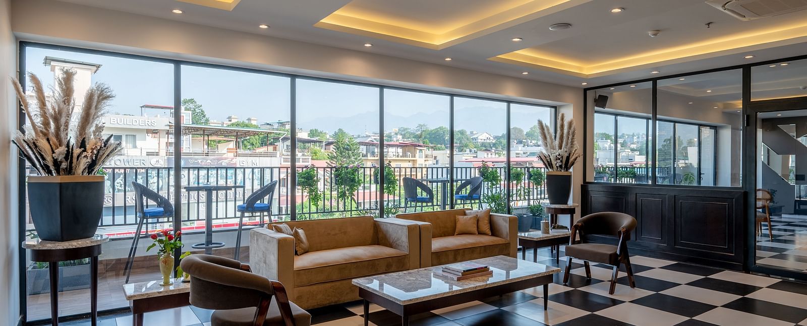 Shot of a bar at Vishranti Hotel Dehradun with chairs, sofas, tables, a counter and checkered floors. 