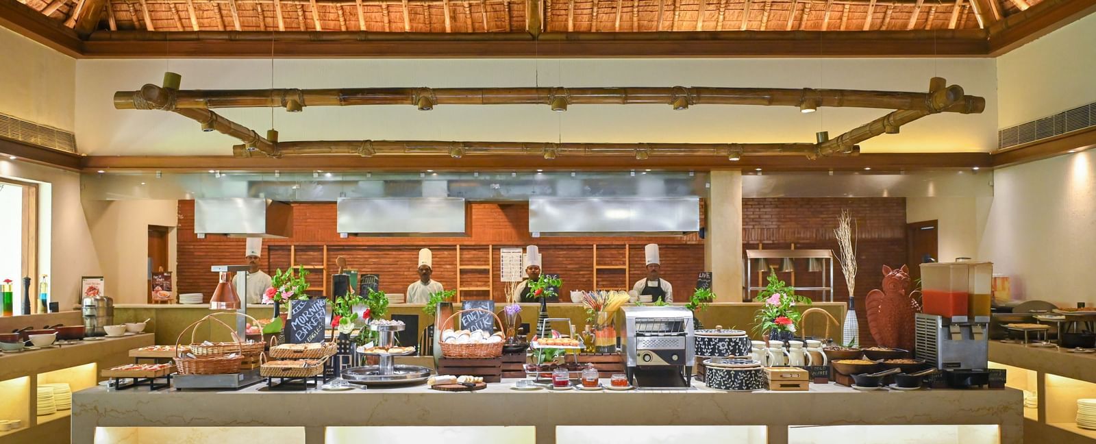 Buffet Counter in Yagna at Vedic Village Spa Resort, featuring high ceilings and chefs lined up behind the counter.