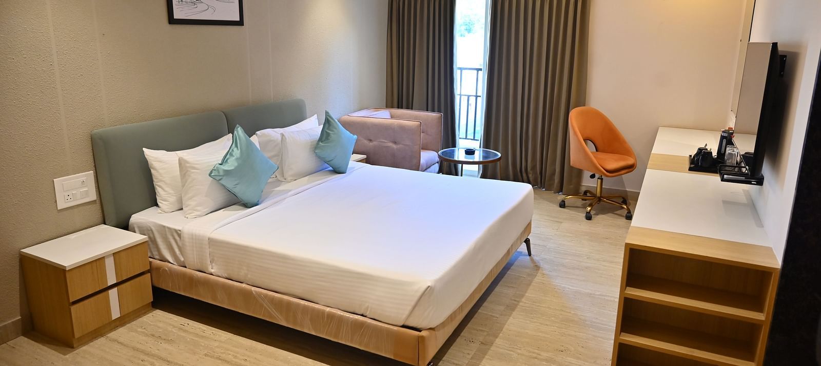 Bright and airy premium room with a big bed, soft chairs, and curtains over large windows, offering plenty of light and modern features at TGI Livancia Hillside