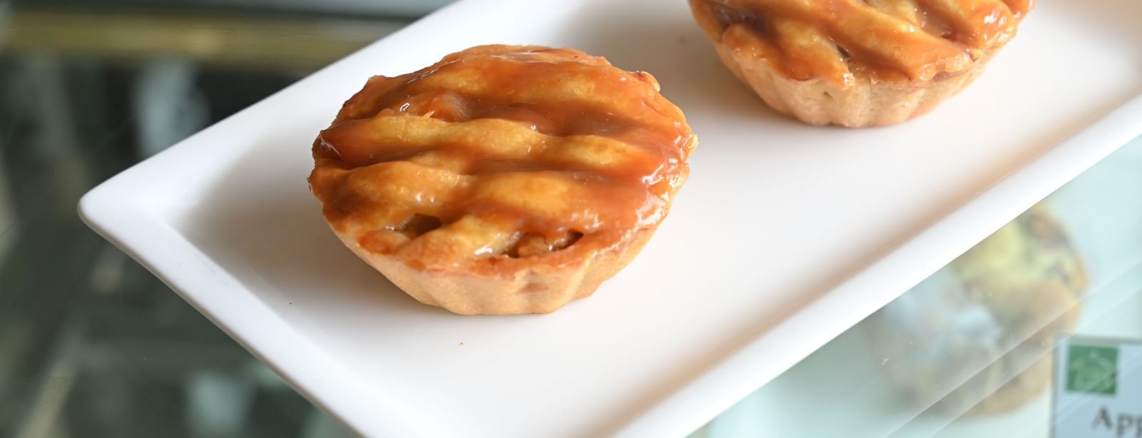 Two small, golden-brown tarts are presented on a white rectangular plate | Vedic Village Spa Resort, Kolkata