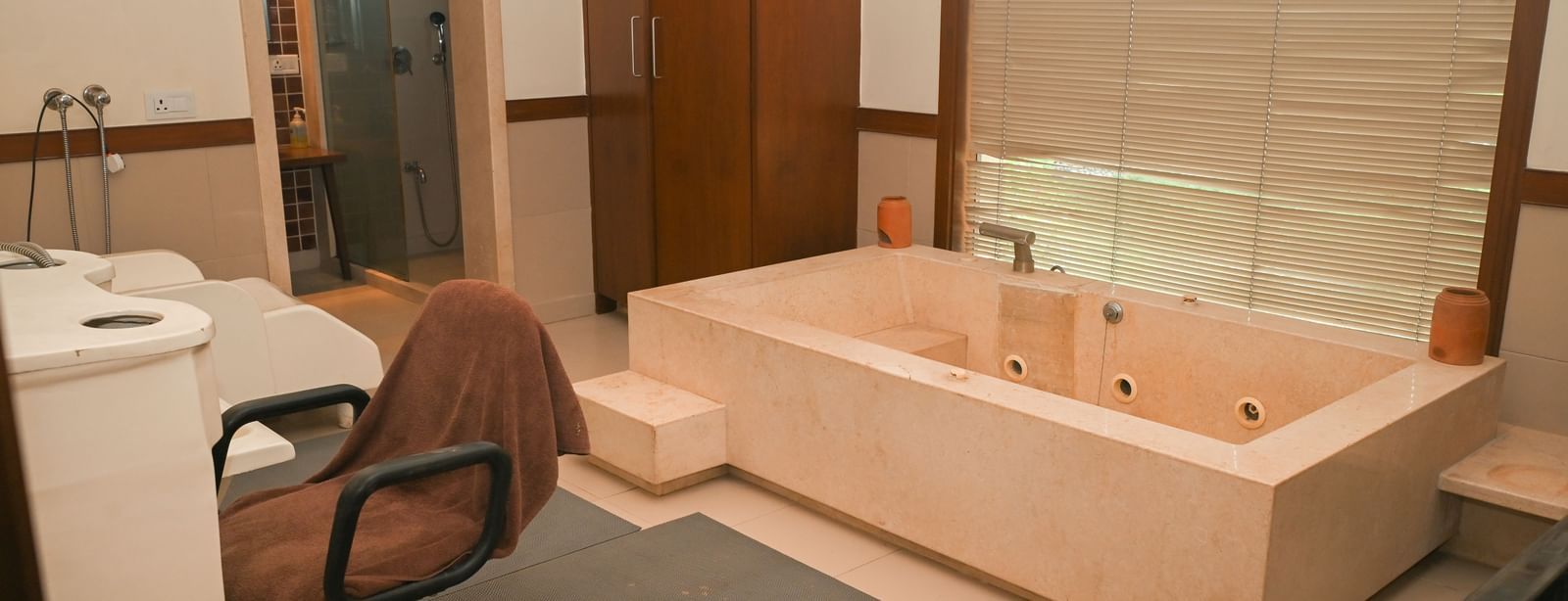 Spa therapy room in Vedic Village Spa Resort, featuring a bathtub and private shower area.