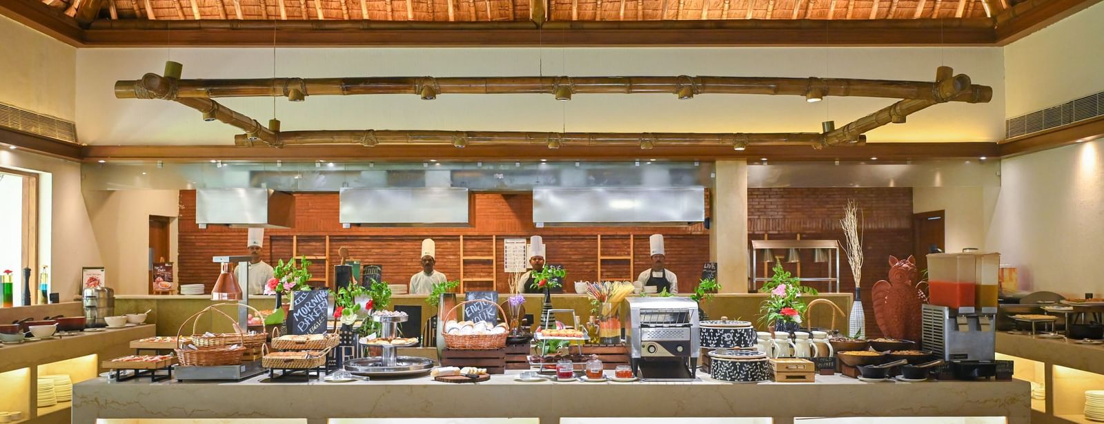 Buffet Counter in Yagna at Vedic Village Spa Resort, featuring high ceilings and chefs lined up behind the counter.