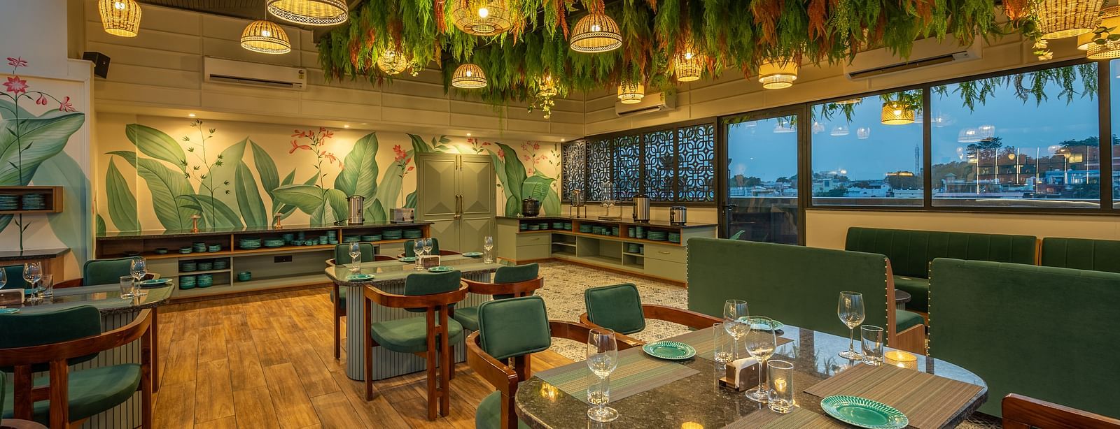 Side shot of interior of The Gaia Gourmet restaurant at Vishranti Hotel, Dehradun, featuring a well-lit dining area with wooden floors.