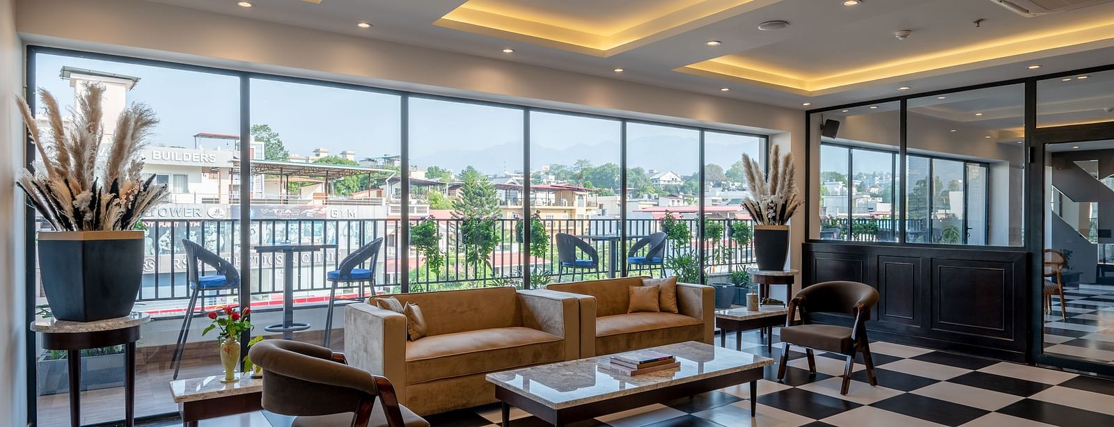 Shot of a bar at Vishranti Hotel Dehradun with chairs, sofas, tables, a counter and checkered floors. 