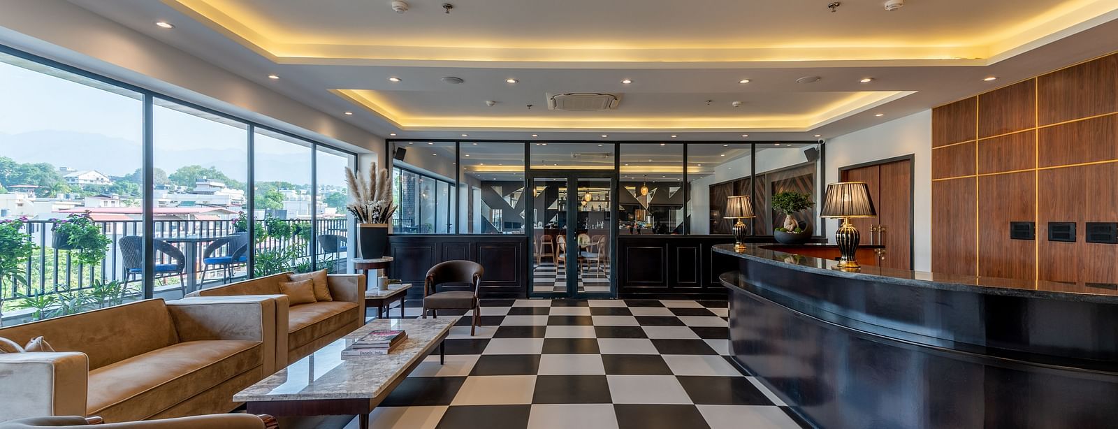 Overview of a bar at Vishranti Hotel Dehradun with chairs table and checkered floors. 