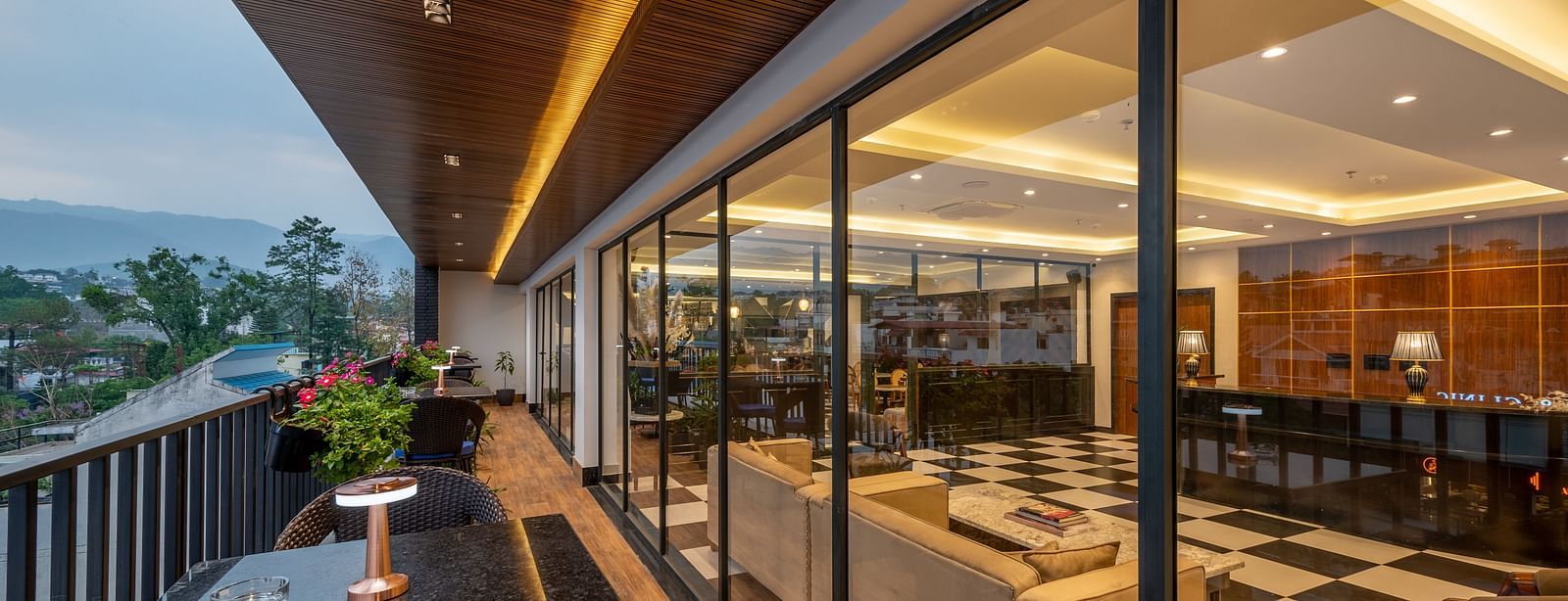 Shot of an outdoor dining area on a balcony, of The Spirit Tribe Restaurant at Vishranti Hotel, Dehradun. The balcony features a wine glasses, a dark-colored metal railing and a dining table.