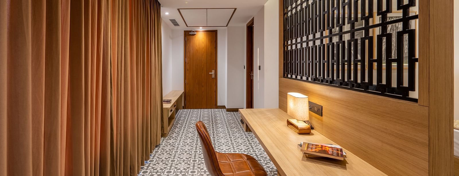 Living area of a suite at Vishranti Hotel, Dehradun featuring a work desk, chair and a metal frame window.