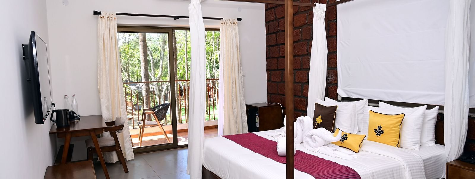 An image of a Premium Cottage featuring a poster bed, a flat TV screen, a work desk and chair, and a balcony - TGI Redolent Resort, Kushalnagar, Coorg