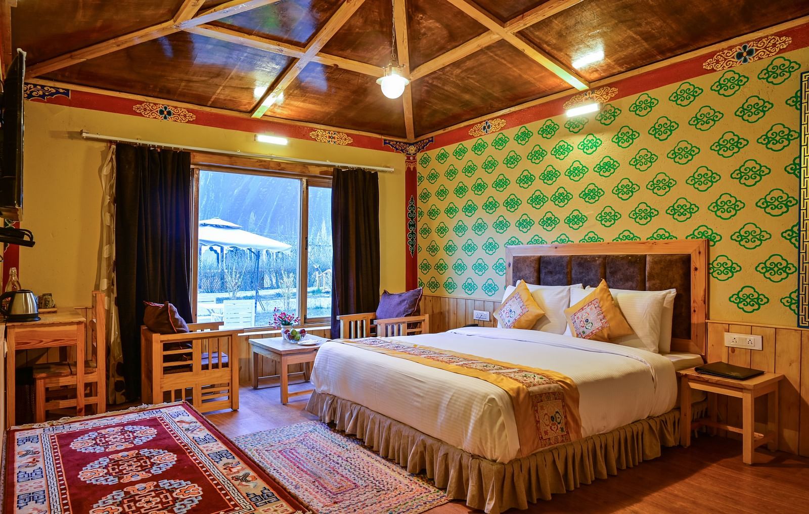 Premium Cottage in White Sands Resort, Ladakh, includes a king size bed, a seating area, and patterned wallpaper.