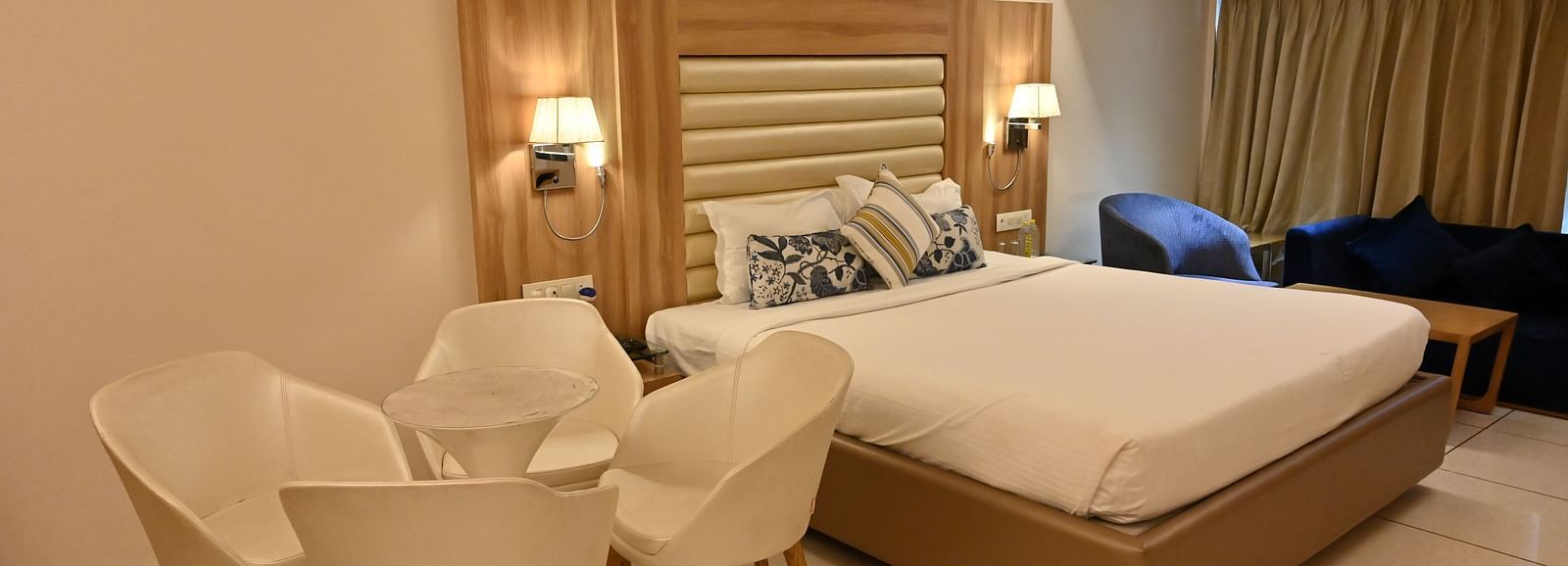 Inviting room at Rang Lords Inn Bharuch, with a neatly made bed, seating, and warm bedside lamps