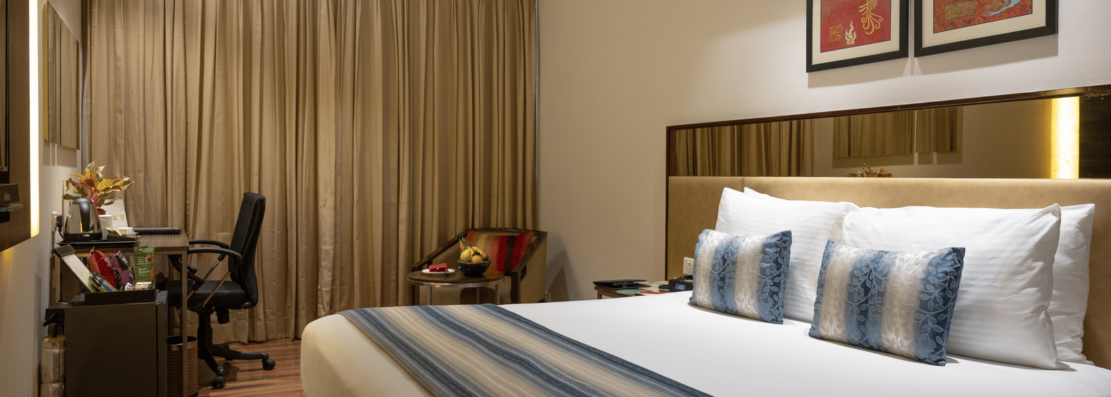 An image of one of the hotel rooms in Kakinada with working table and a chair at long shot view of the hotel corridors at Grand Kakinada by GRT Hotels