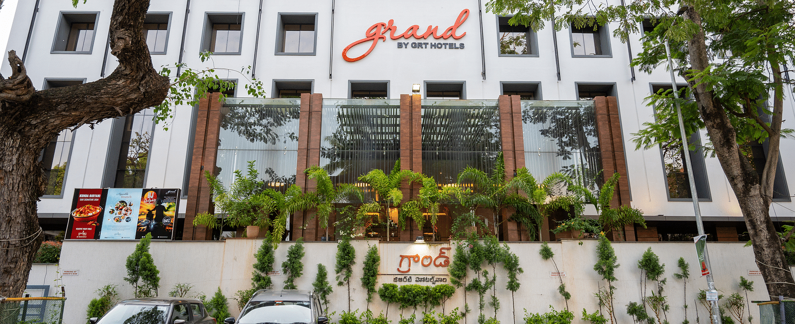 parking space of Grand Kakinada by GRT Hotels covered with plants and trees