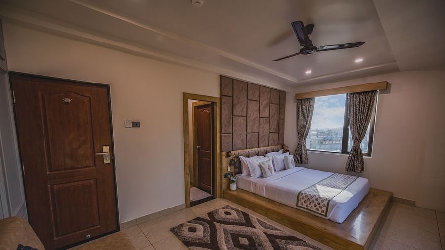 Clarks Collection Somnath room with double bed, wooden door, beige flooring, and windows with outside view.