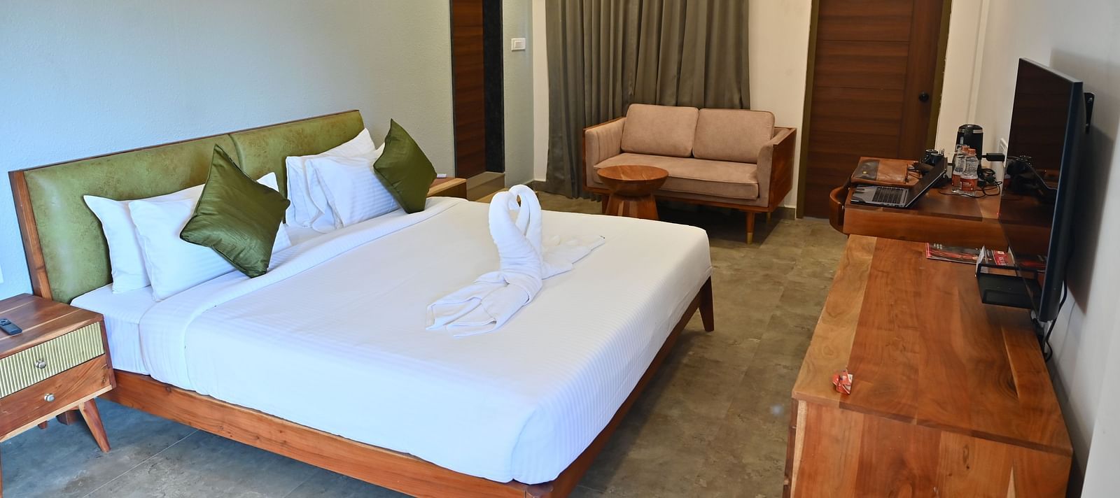 Spacious suite with a large bed, pillows, a sofa, and a wooden desk with modern amenities at TGI Livancia Hillside