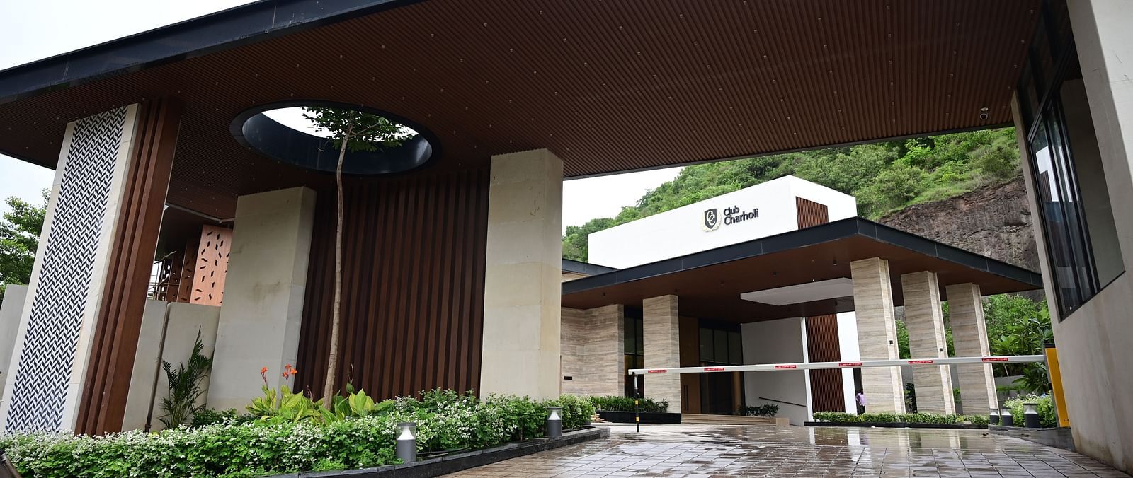 Entrance with a covered drive and gate, leading to a building set against a hillside.
