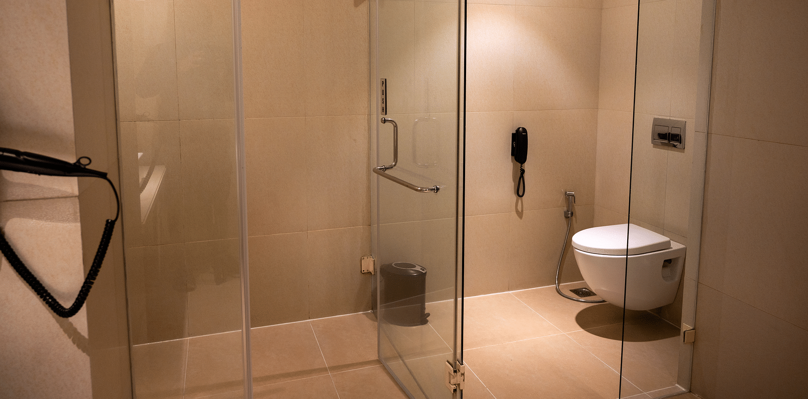 An image of a bathroom with a western toilet and shower area at  Grand Kakinada by GRT Hotels