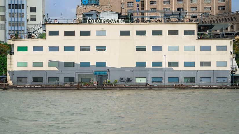 Exterior view of a waterfront building with multiple windows, reflecting on the calm water surface- hotel Polo Flotel