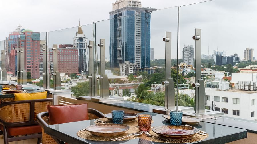 Rooftop restaurant with city skyline views and neatly set dining tables arranged along the railing.