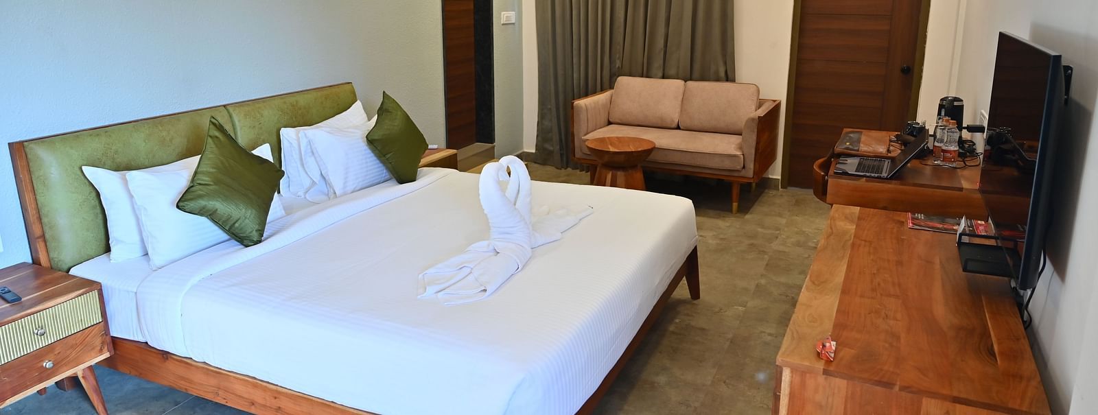 Spacious suite with a large bed, pillows, a sofa, and a wooden desk with modern amenities at TGI Livancia Hillside