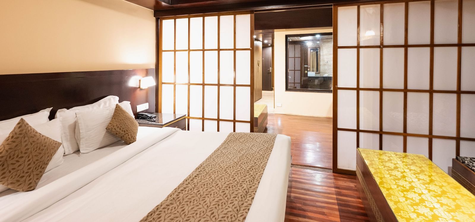 A bedroom with a comfortable bed, sliding doors, and warm lighting leading to another room at Avianna Hungry Jack, Gangtok.