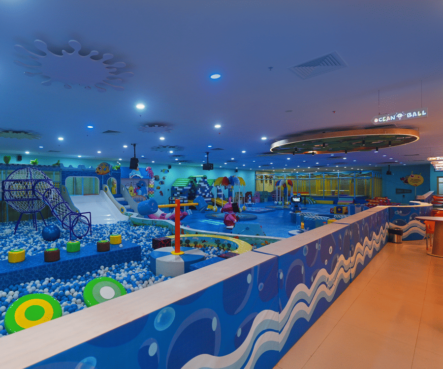 Indoor play area with blue walls, a painted mural, and a long, wavy play structure.