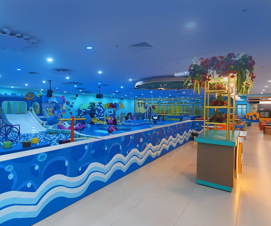 Large indoor play area with a massive ball pit, slides, and climbing structures, under bright lights.
