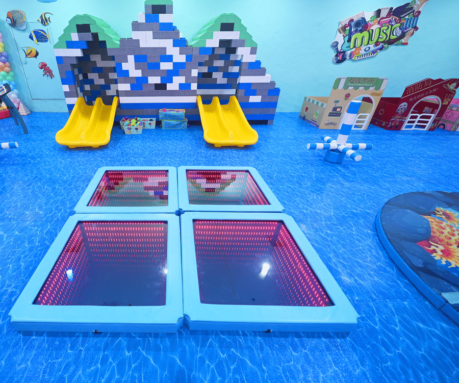 Indoor playground with blue flooring, slides, and various play structures, viewed from above.