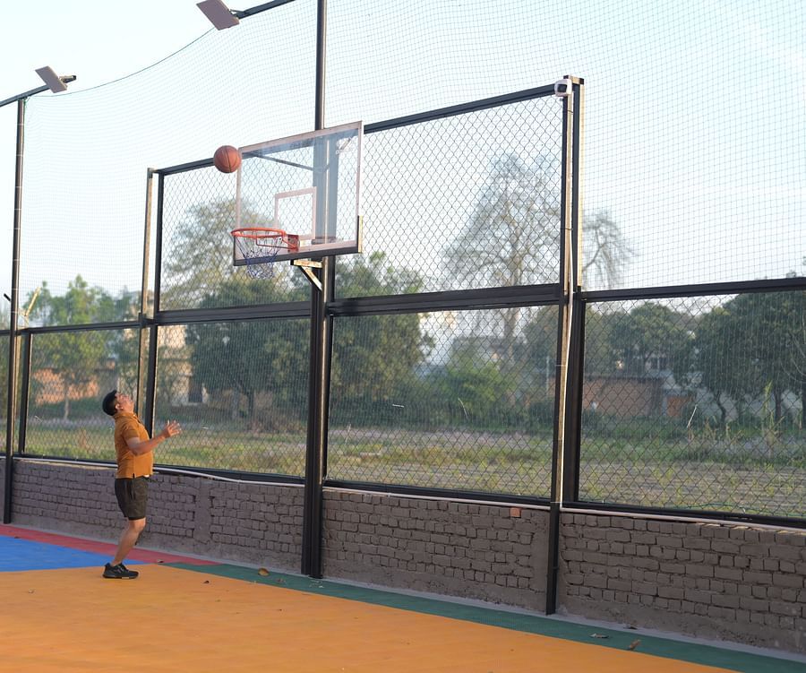 A guy playing basketball alone on a court, with lush greenery in the background - Clarks Safari, Haridwar