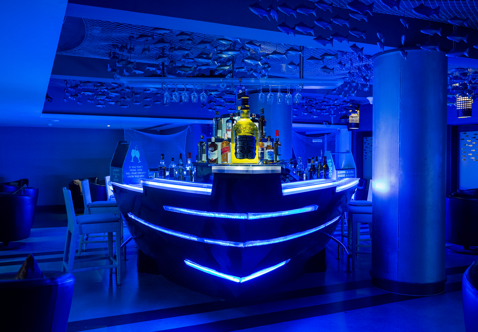 An image of ship themed bar illuminating blue lights at image of an event hall with tables and chairs at Grand Kakinada by GRT Hotels