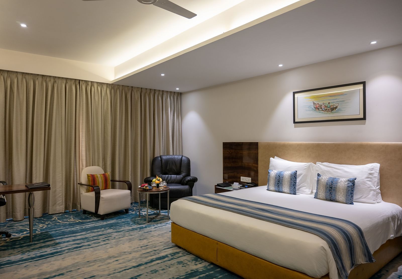 an image of a bedroom with a paining on top of the headboard at Grand Kakinada by GRT Hotels