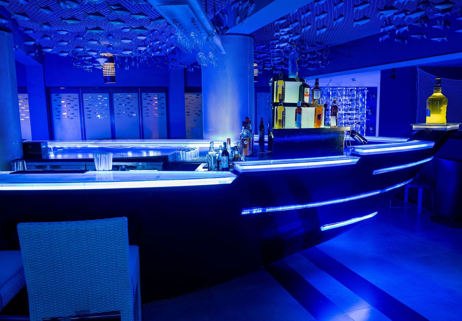 An image of ship shaped bar with metal fishes hanging from the ceiling at image of an event hall with tables and chairs at Grand Kakinada by GRT Hotels