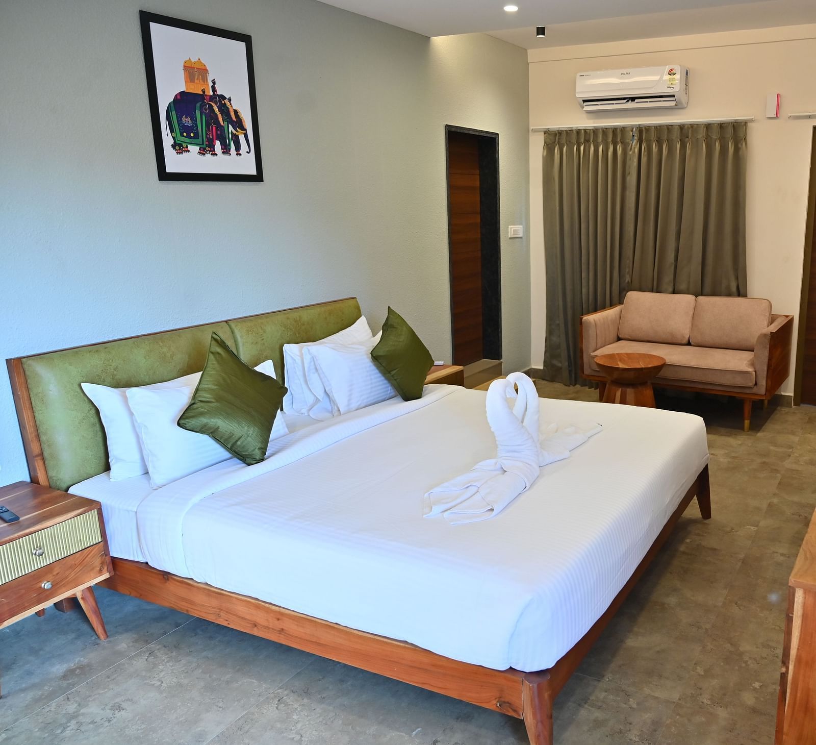 Spacious suite with a large bed, pillows, a sofa, and a wooden desk with modern amenities at TGI Livancia Hillside
