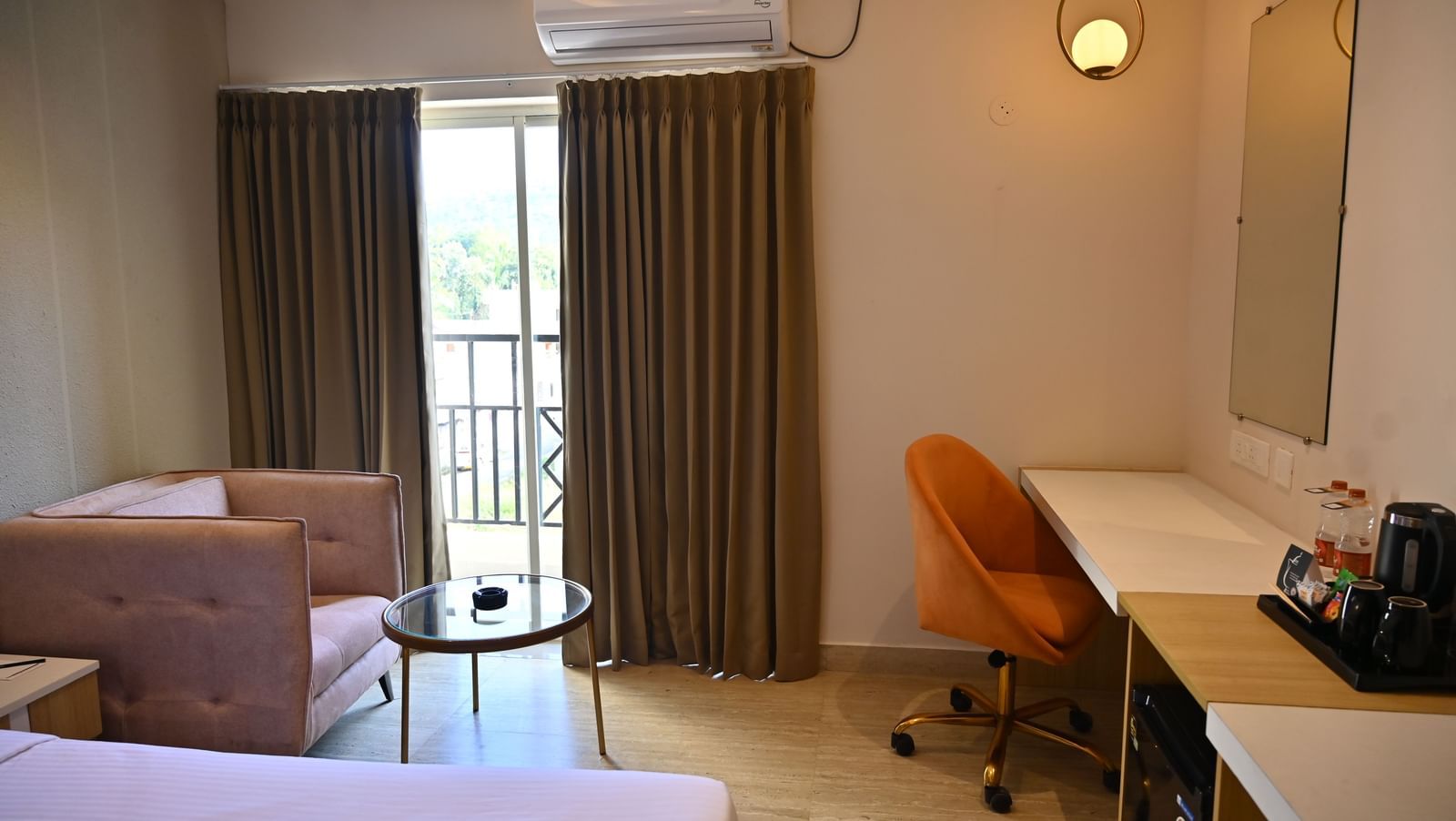 Premium room corner with a chair, a small glass table, and a desk near a sliding door that opens to a private balcony at TGI Livancia Hillside