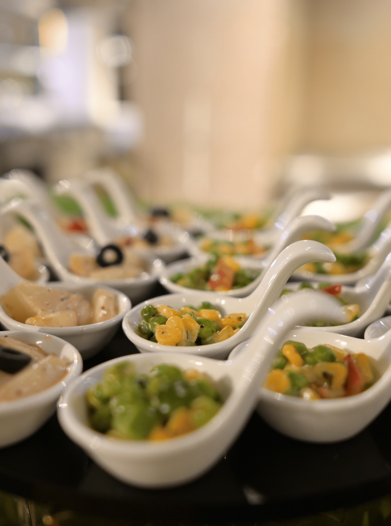 A close-up shot of elegant ceramic spoons filled with assorted canapes and appetisers at Pushkara Resort & Spa.