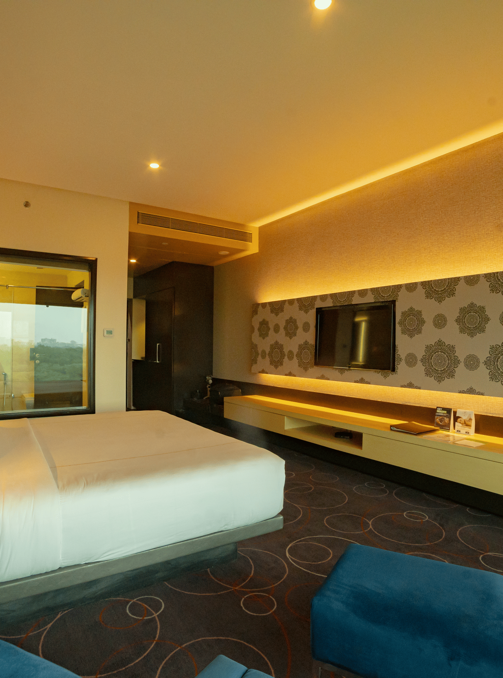 Luxury hotel room with modern lighting and blue seating at Narayani Heights Hotel & Resorts, Ahmedabad.