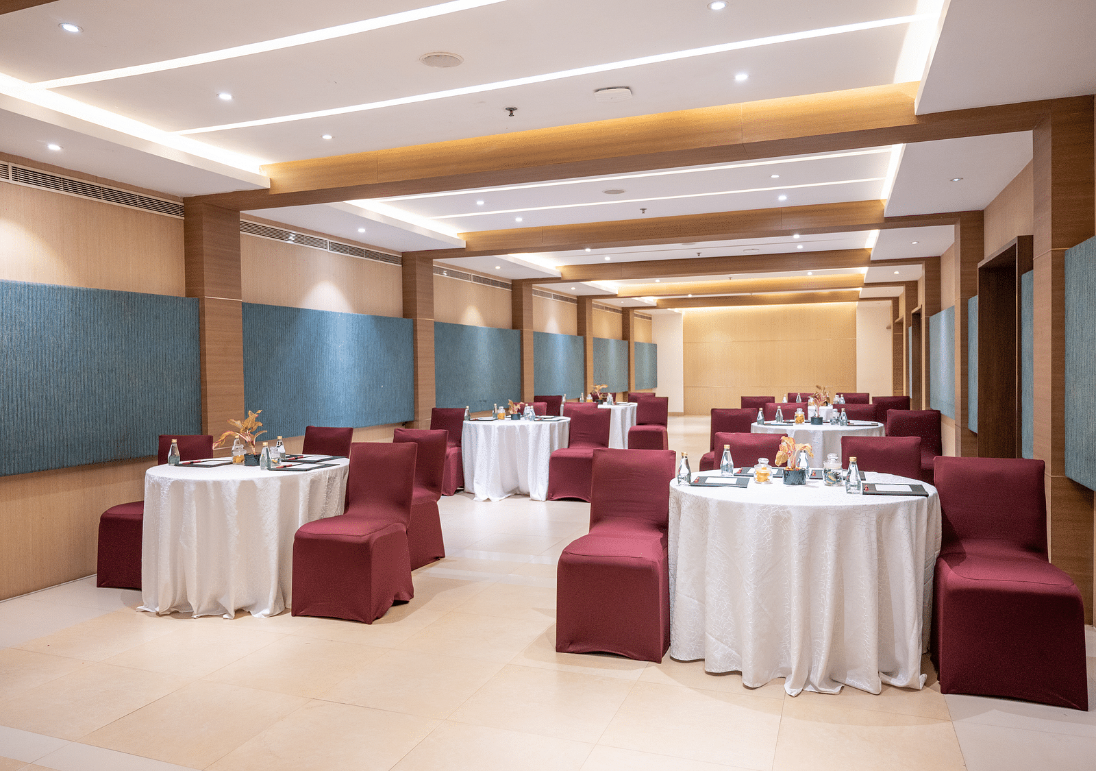image of an event hall with tables and chairs at Grand Kakinada by GRT Hotels