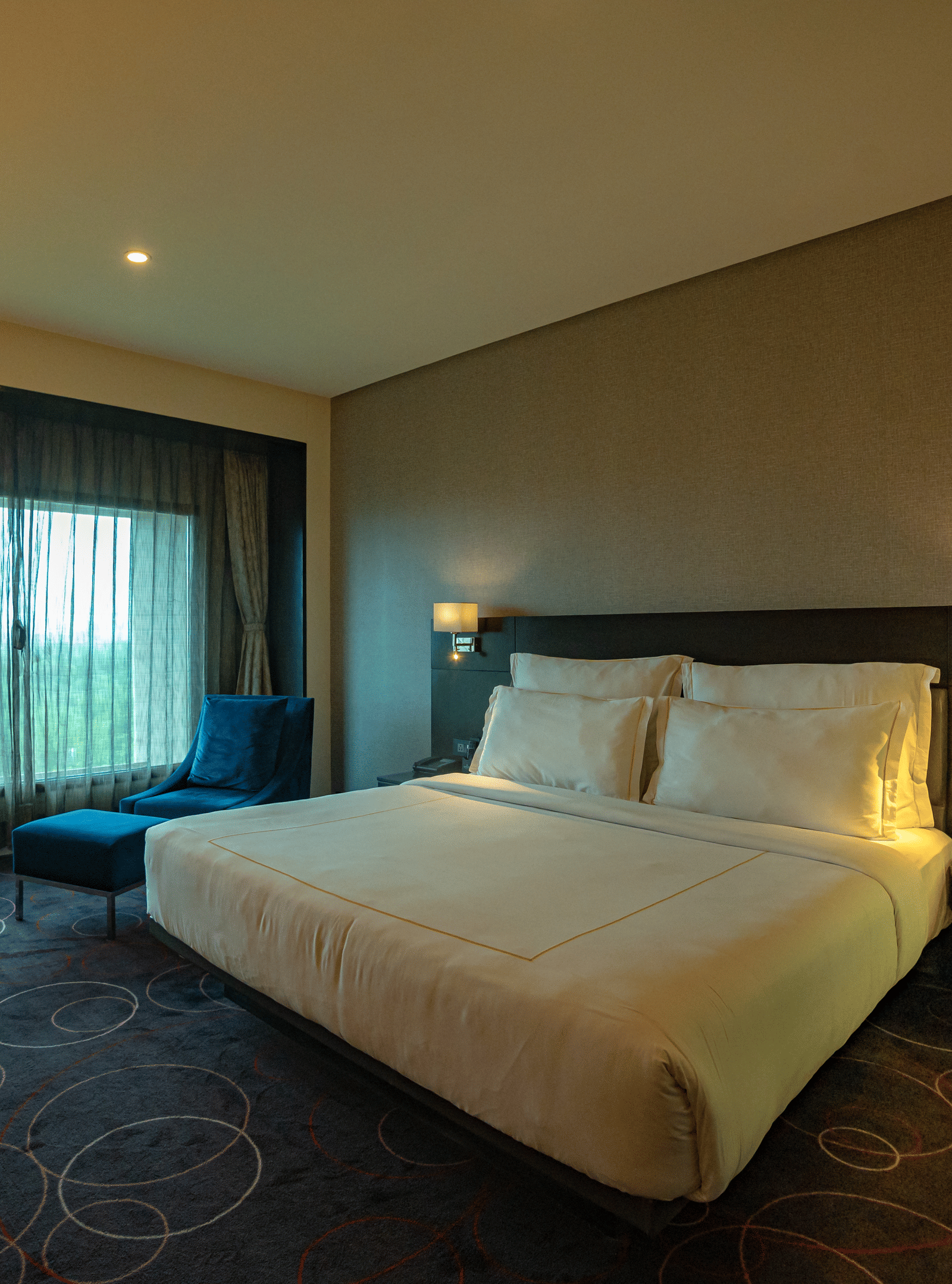 Spacious guest room with a large bed, large windows, and ambient lighting – Narayani Heights Hotel & Resorts