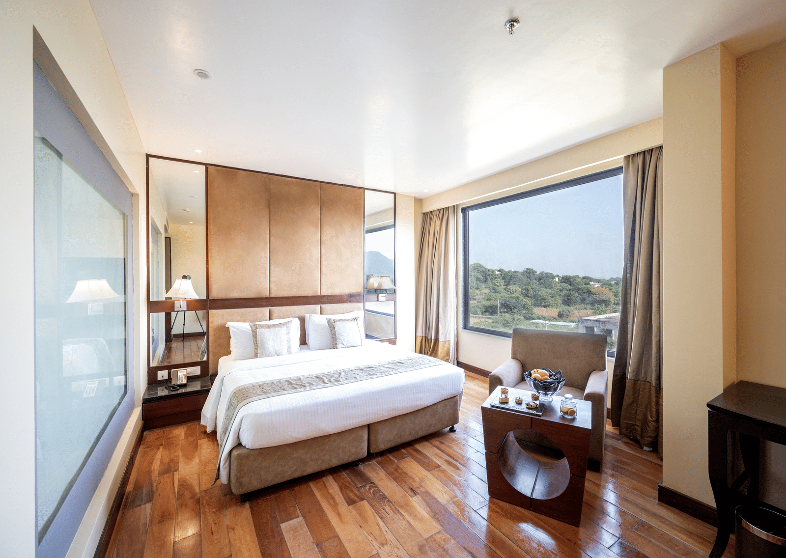 Premium Room at Essentia Luxury Resort & Spa, Udaipur featuring a plush bed and a seating space at its foot by the window