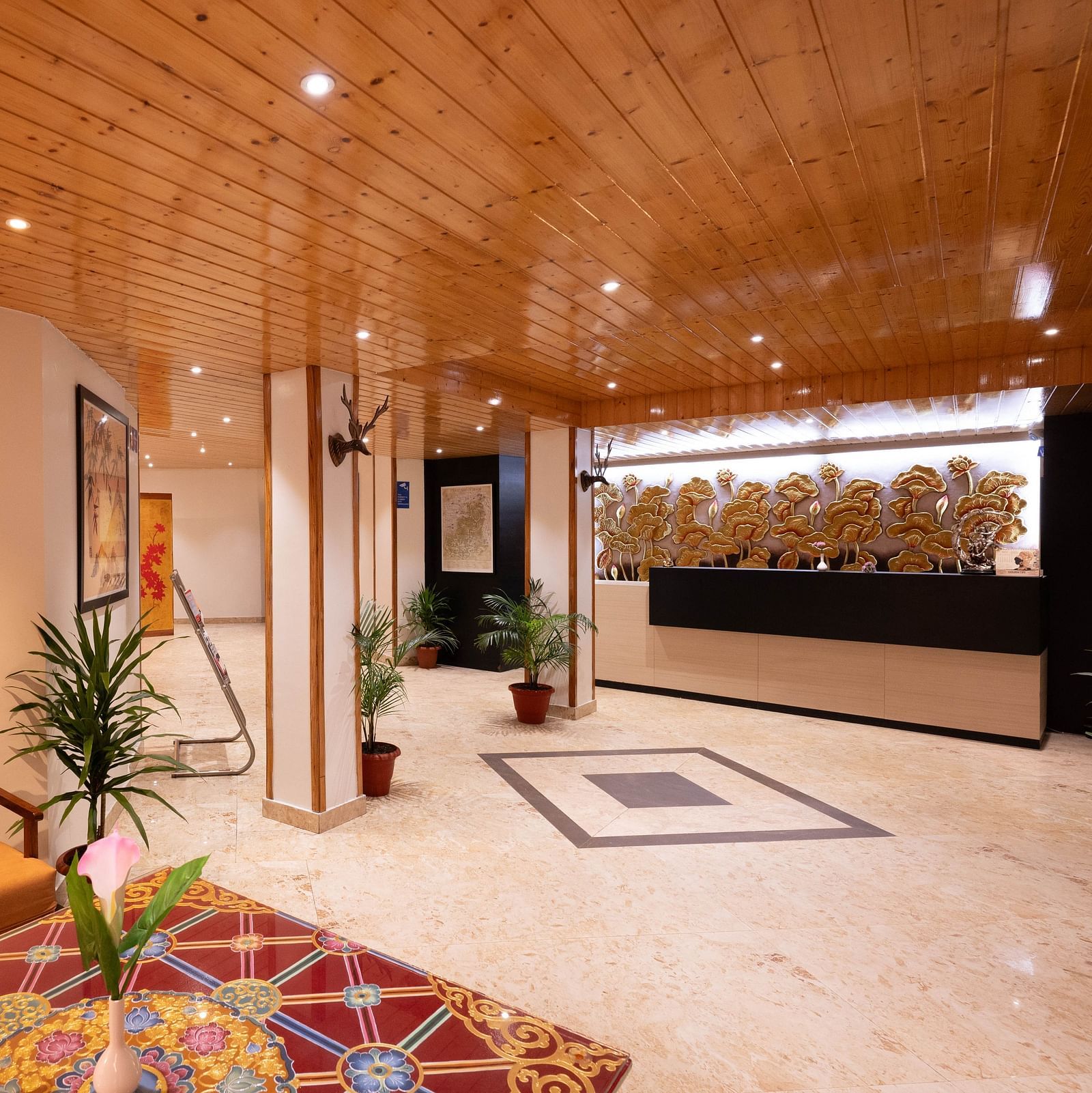 A lobby area with wooden interiors, vibrant decor, and a view of the reception desk at Avianna Hungry Jack, Gangtok.