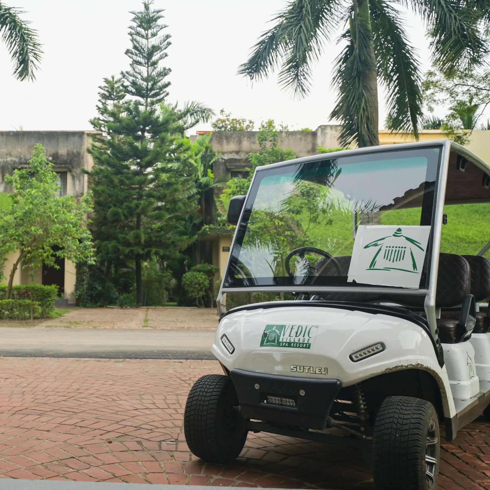 An internal transfortation buggy in Vedic Village Spa Resort stationed against a backdrop of greenery.